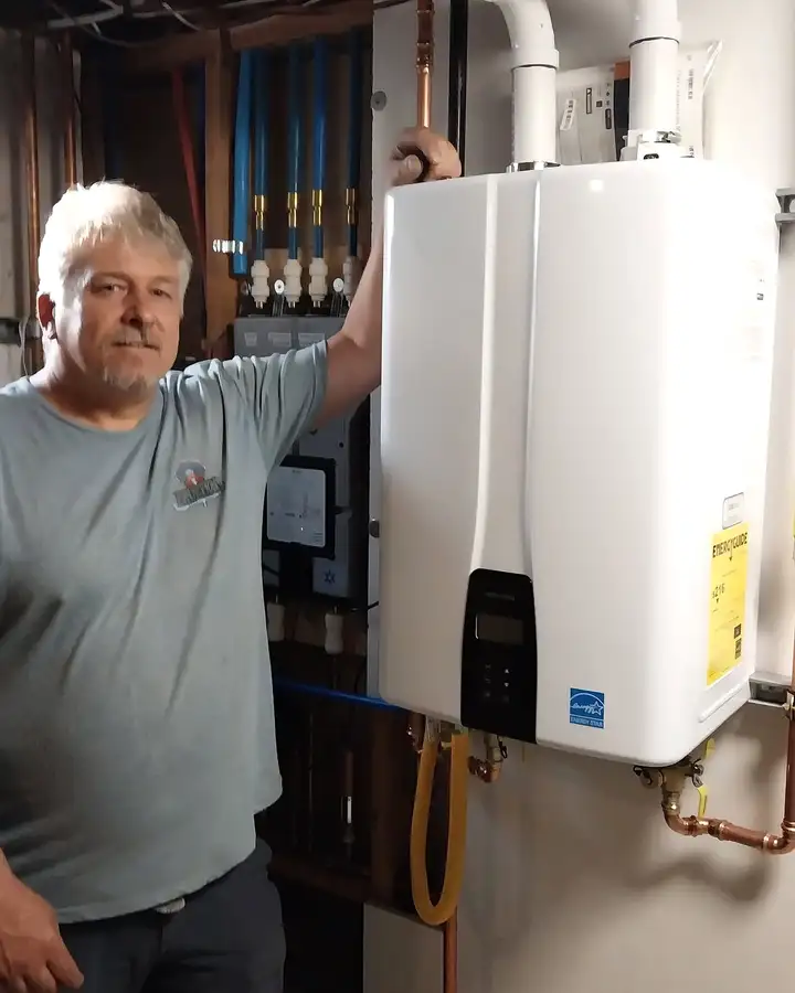 Jon Goble, owner of Eruption Plumbing & Drains, next to a wall-mounted tankless water heater he installed